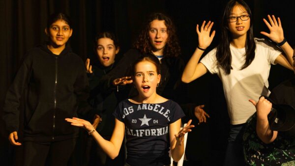 A group of students looks to the front of the camera with startled expressions